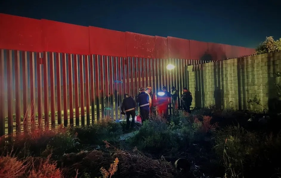 Migrante con hijo en brazos, caen en su intento por cruzar muro fronterizo; uno muere