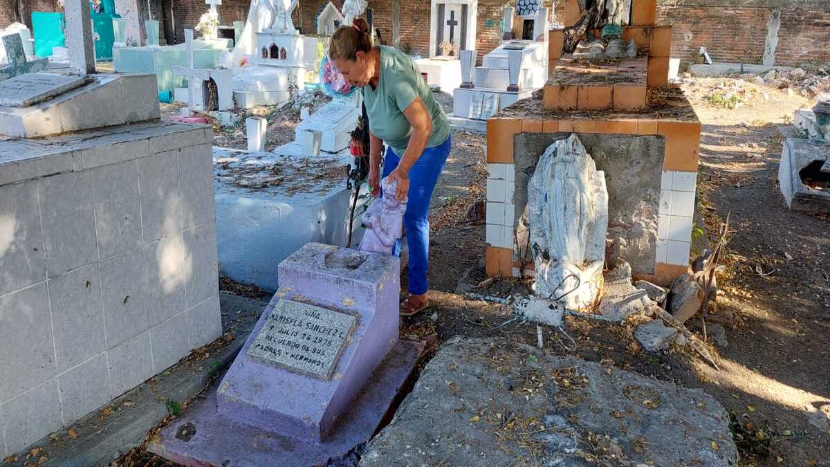 La señora Guadalupe reparte las flores que le lleva a su hija con una tumba abandonada de una niña