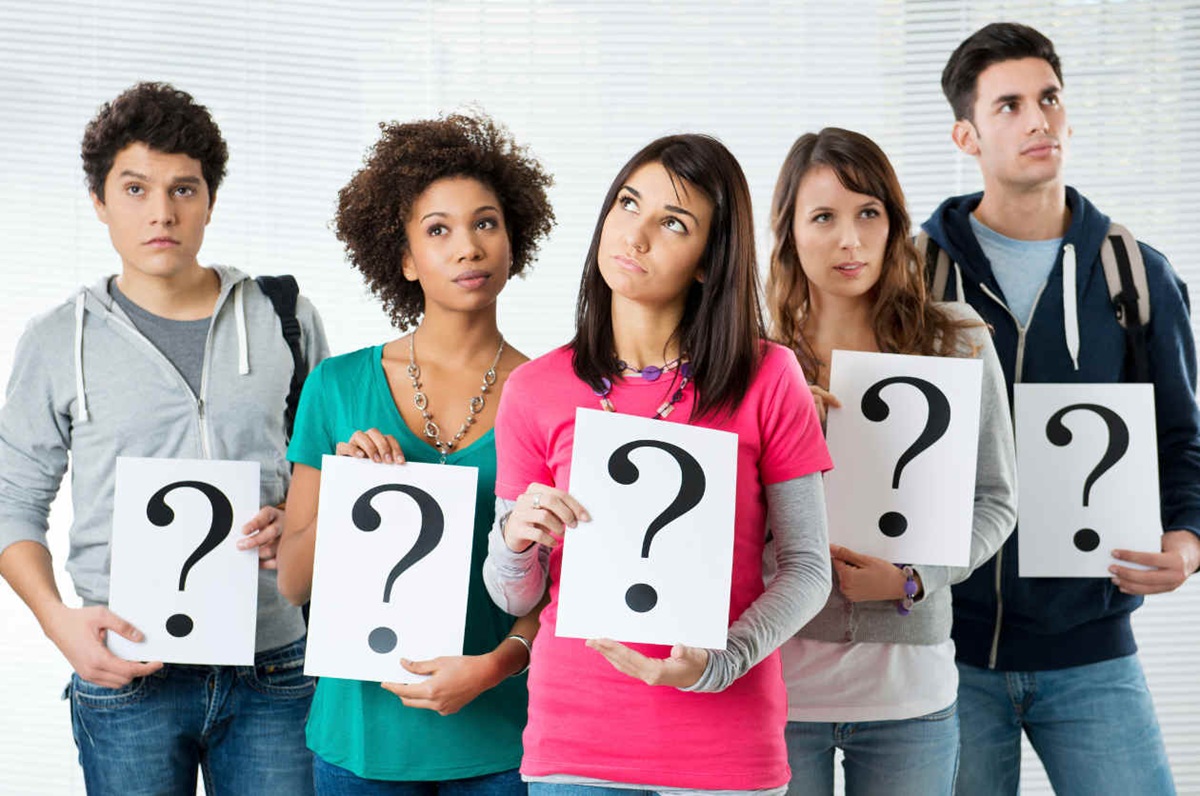 Jóvenes sosteniendo carteles de signo de interrogación