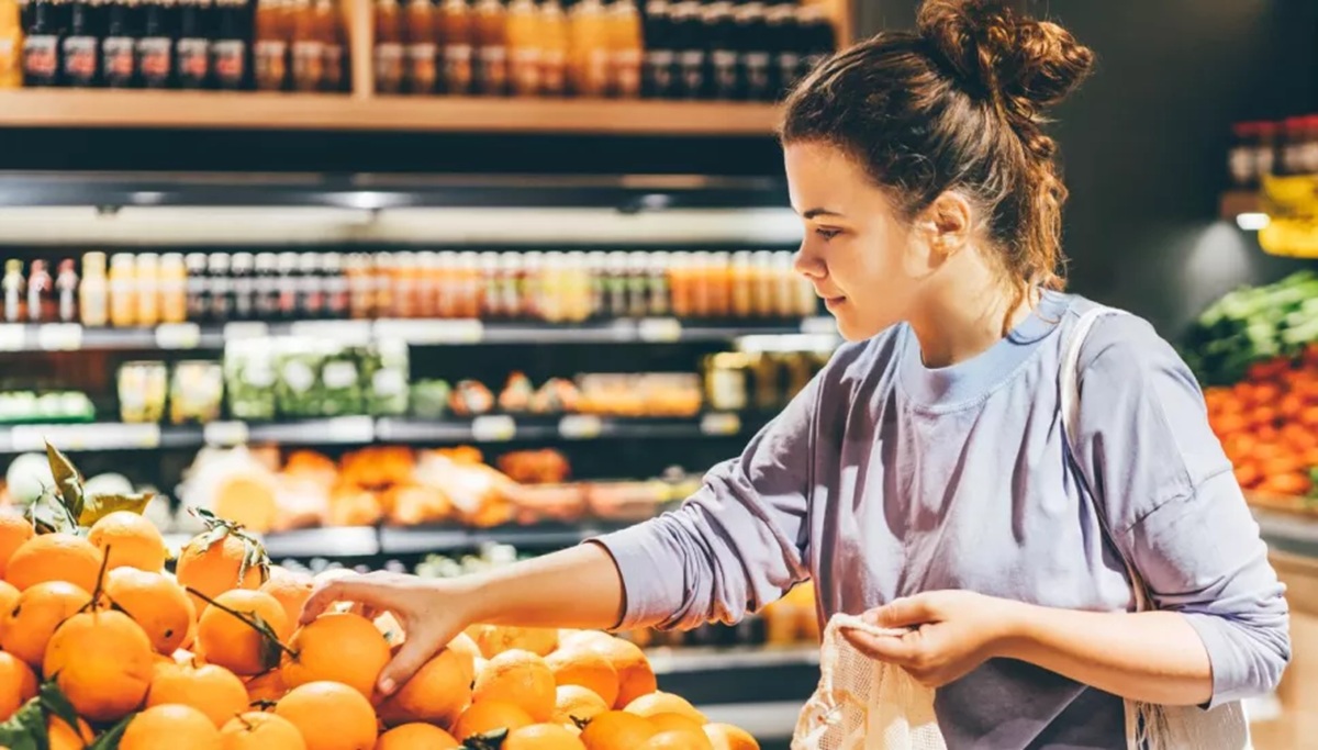Joven mujer eligiendo naranjas en el súper