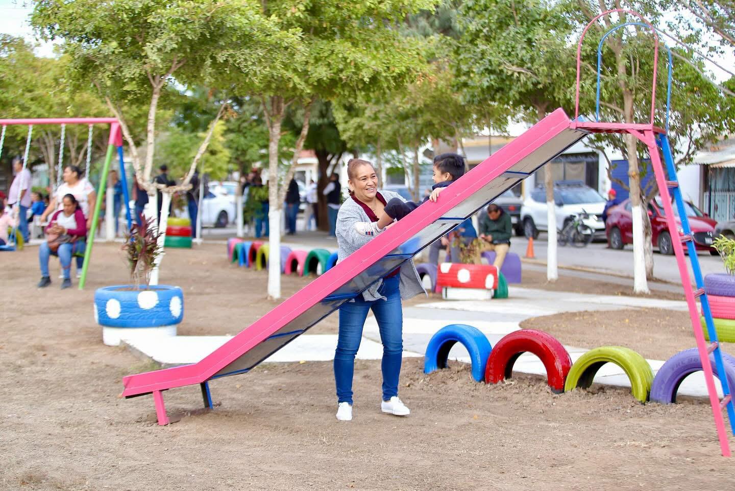 Mamá jugando con hijos en resbaladilla