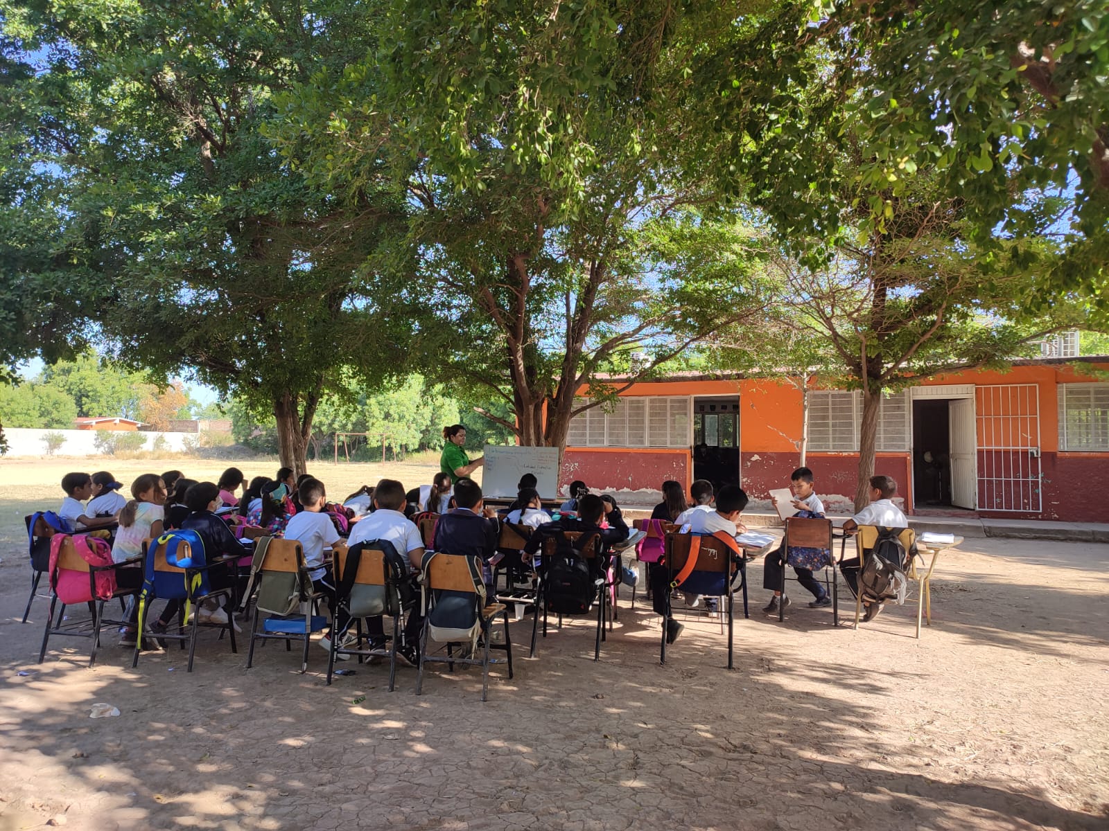Niños tomando clases a la intemperie
