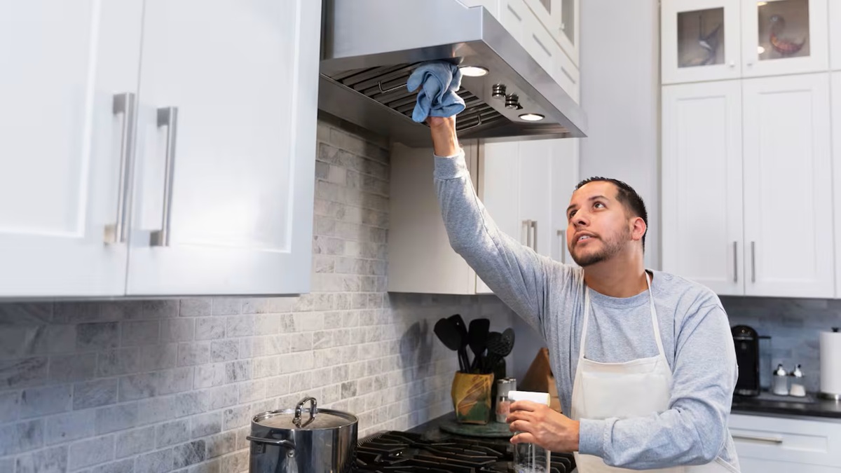 Hombre joven limpiando la campana de la cocina