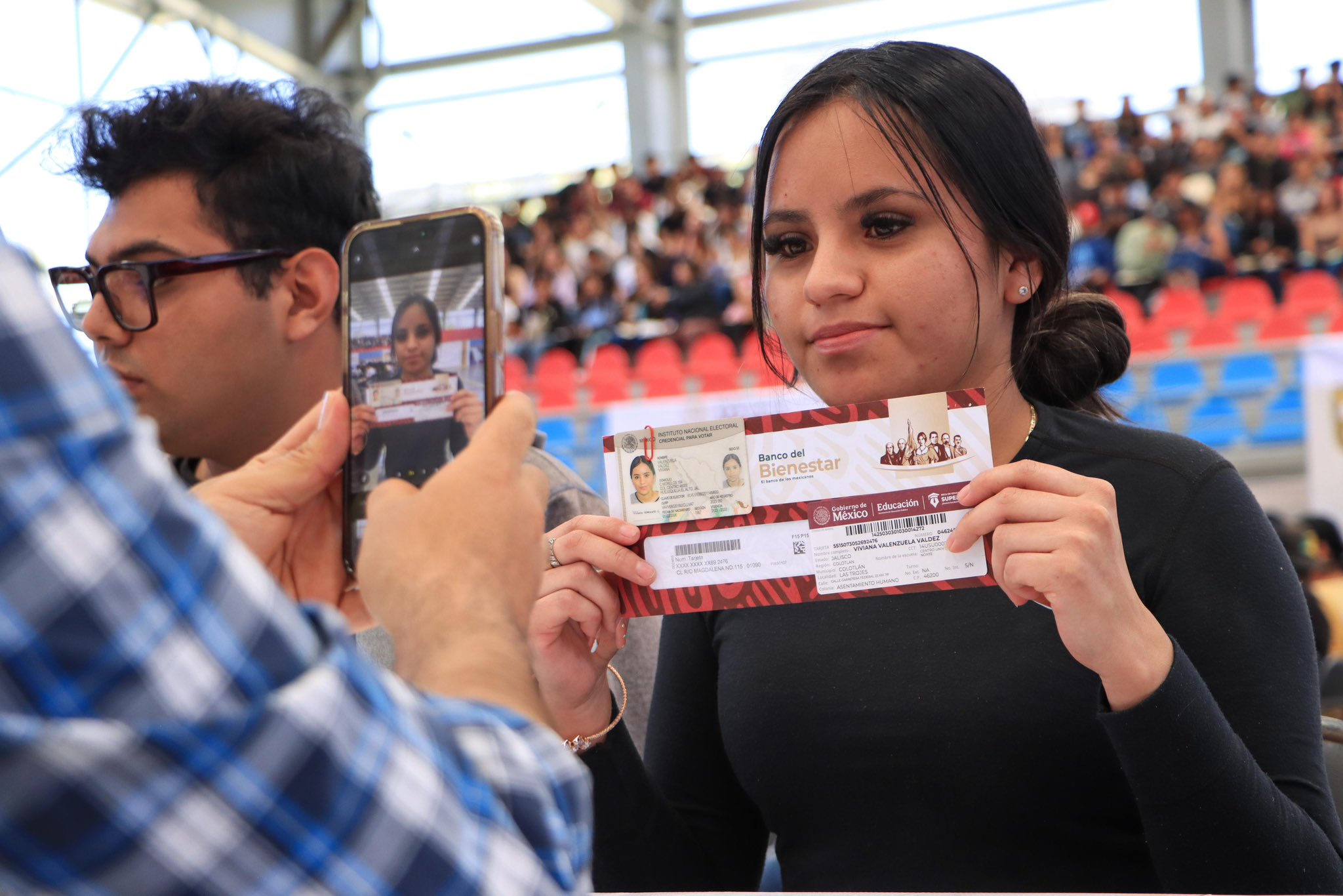 Joven mujer recibiendo su tarjeta de Jóvenes Construyendo el Futuro