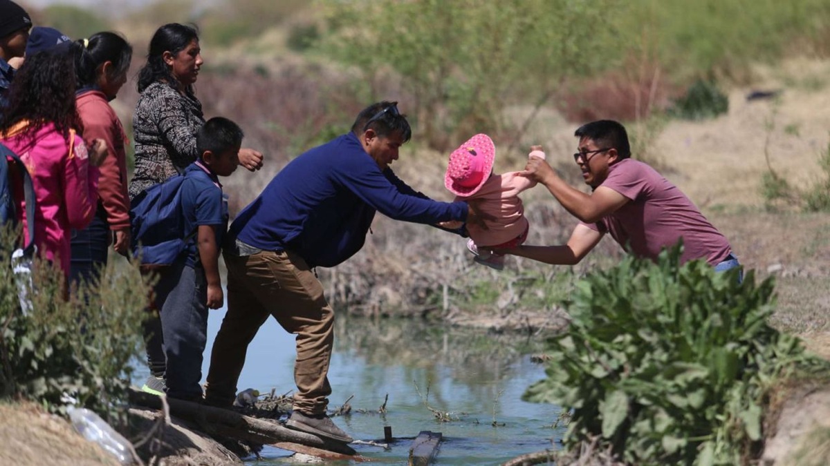 Grupo de migrantes con sus familias atravesando un arrollo
