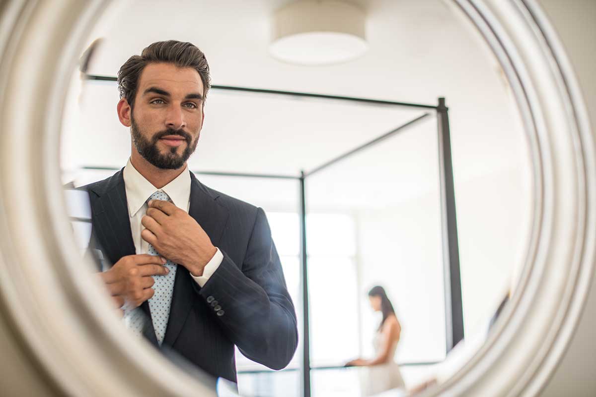 Hombre con traje viéndose al espejo