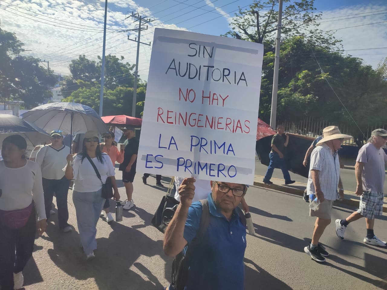 Persona sostiene cartulina donde se lee: Sin auditorias no hay reingenierías, la prima es primero
