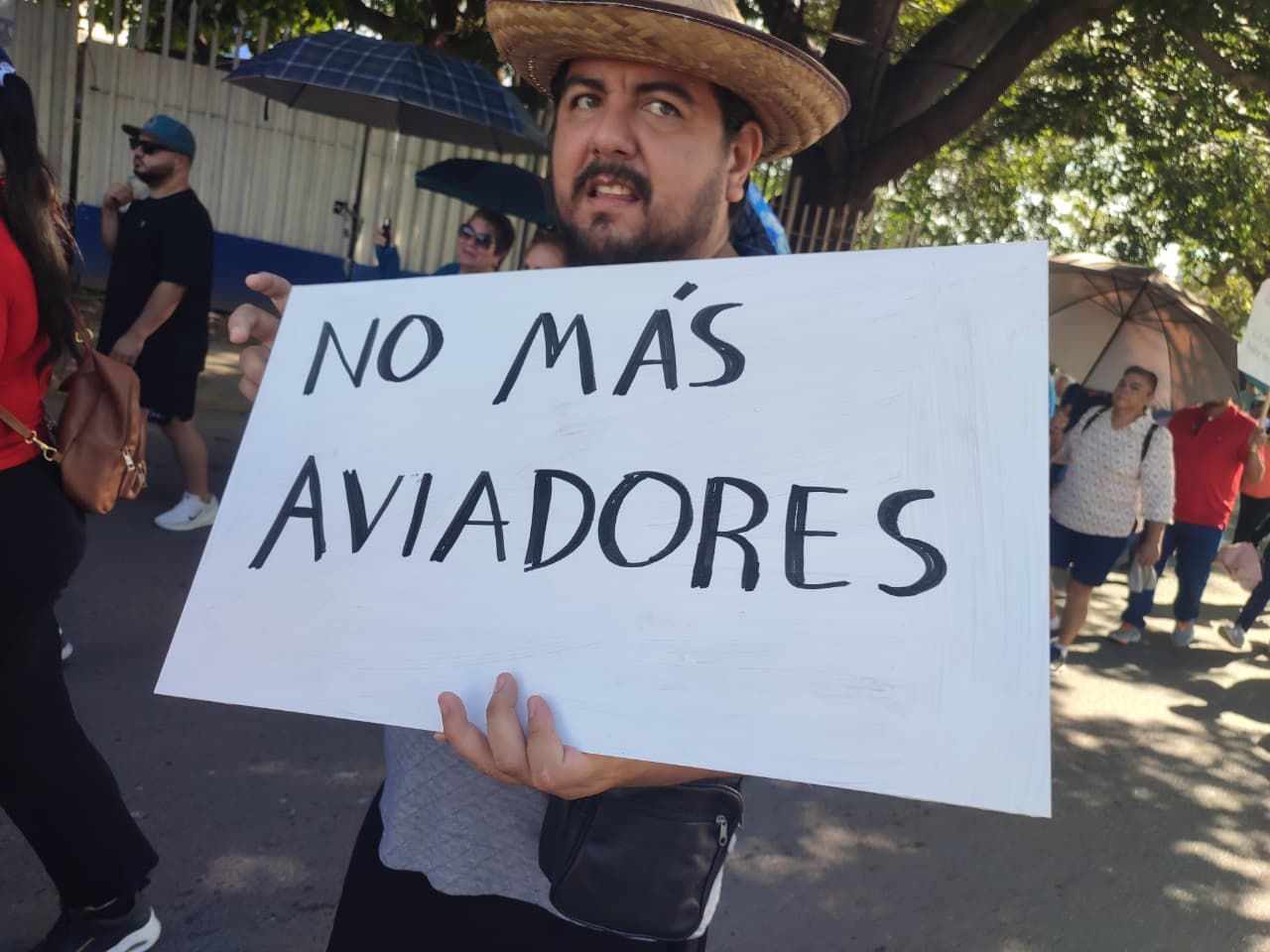Persona sostiene cartulina donde se lee: No más aviadores