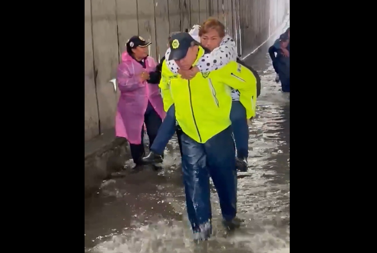 Policía de la Ciudad de México cargando a pasajera por inundaciones