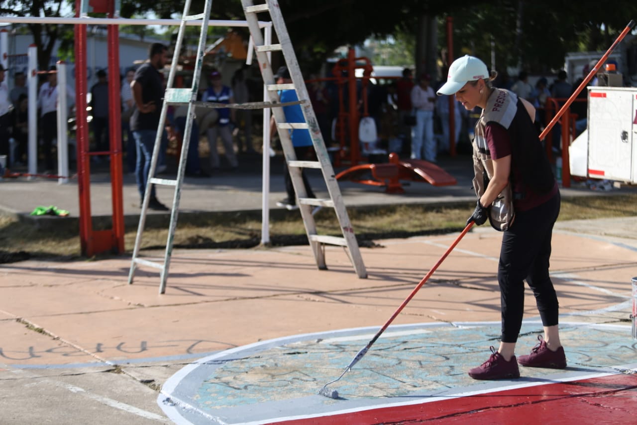 mujer pintando cancha de basquetbol en parque público