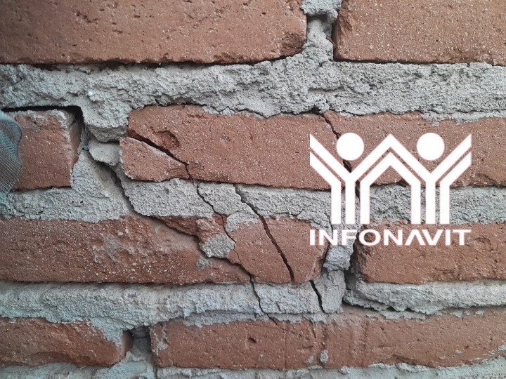 Pared de ladrillo dañada y logotipo del infonavit