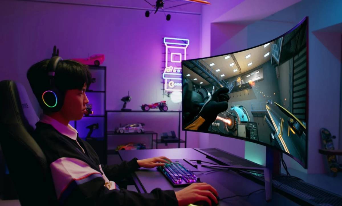Un gamer con auriculares, sentado en un escritorio con un monitor curvo y accesorios de juego