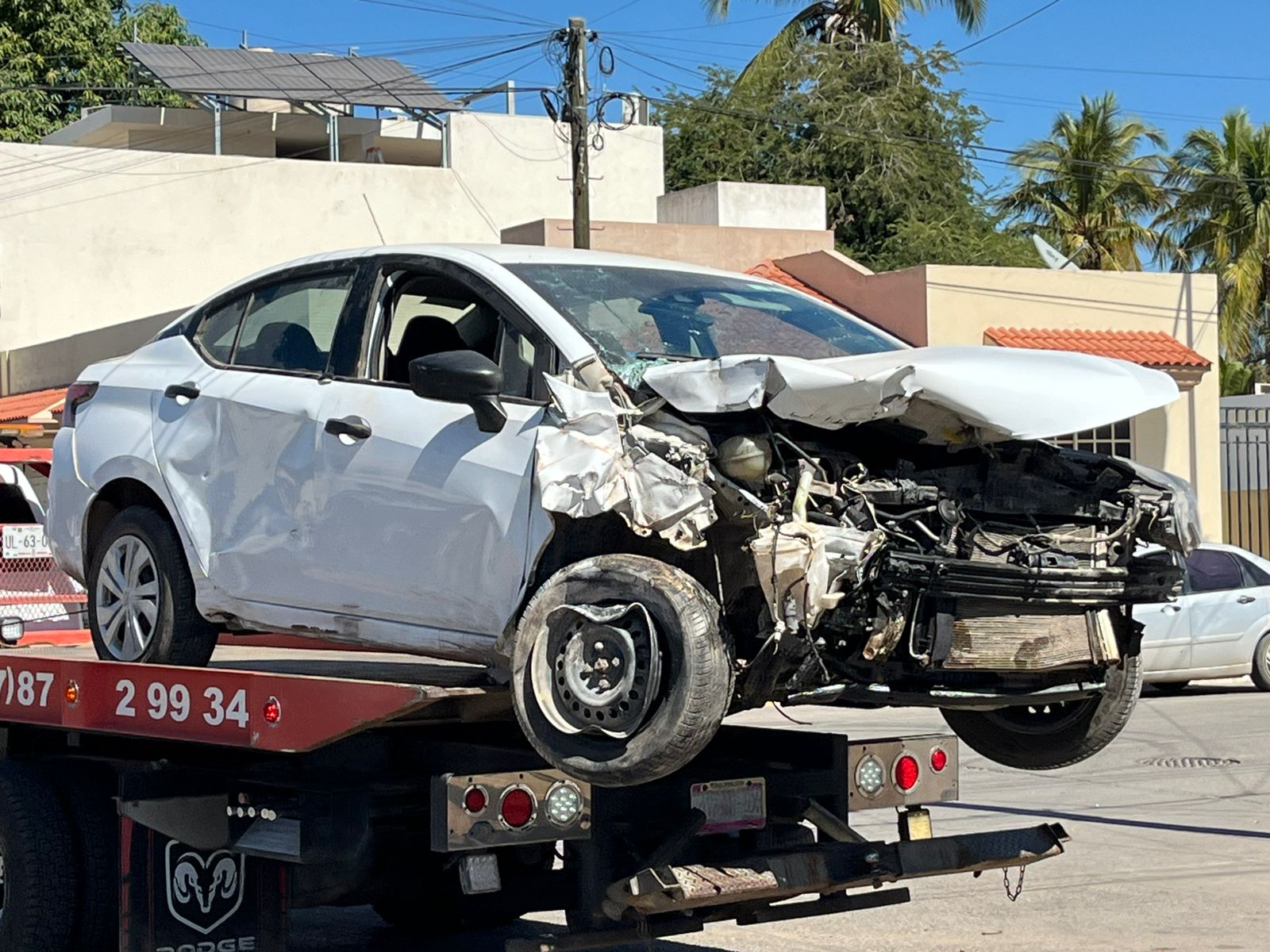 Nissan Versa blanco accidentado arriba de una grúa