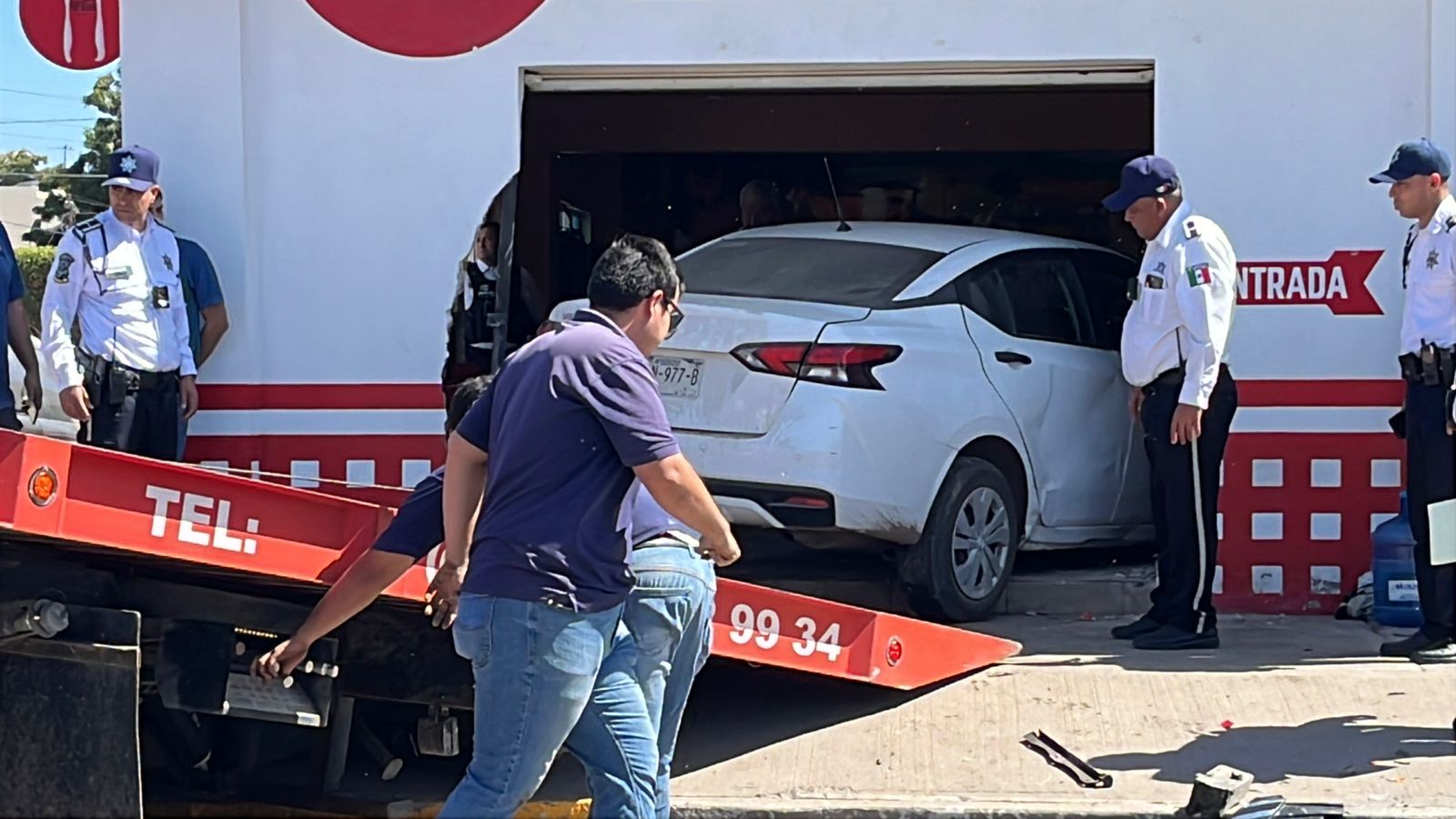 Nissan Versa blanco estrellado en la fachada en un local