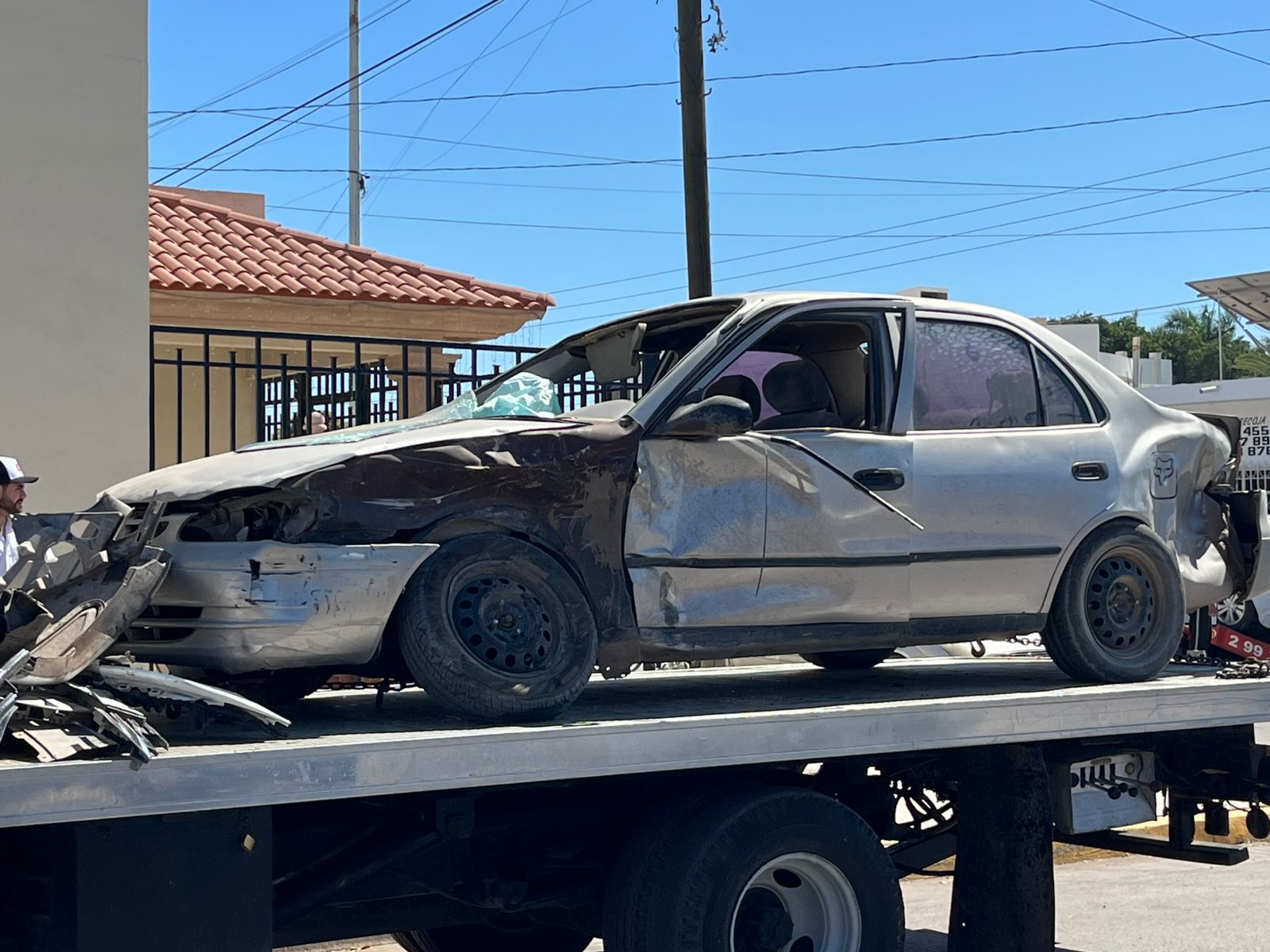 Toyota Corolla gris accidentado arriba de una grúa