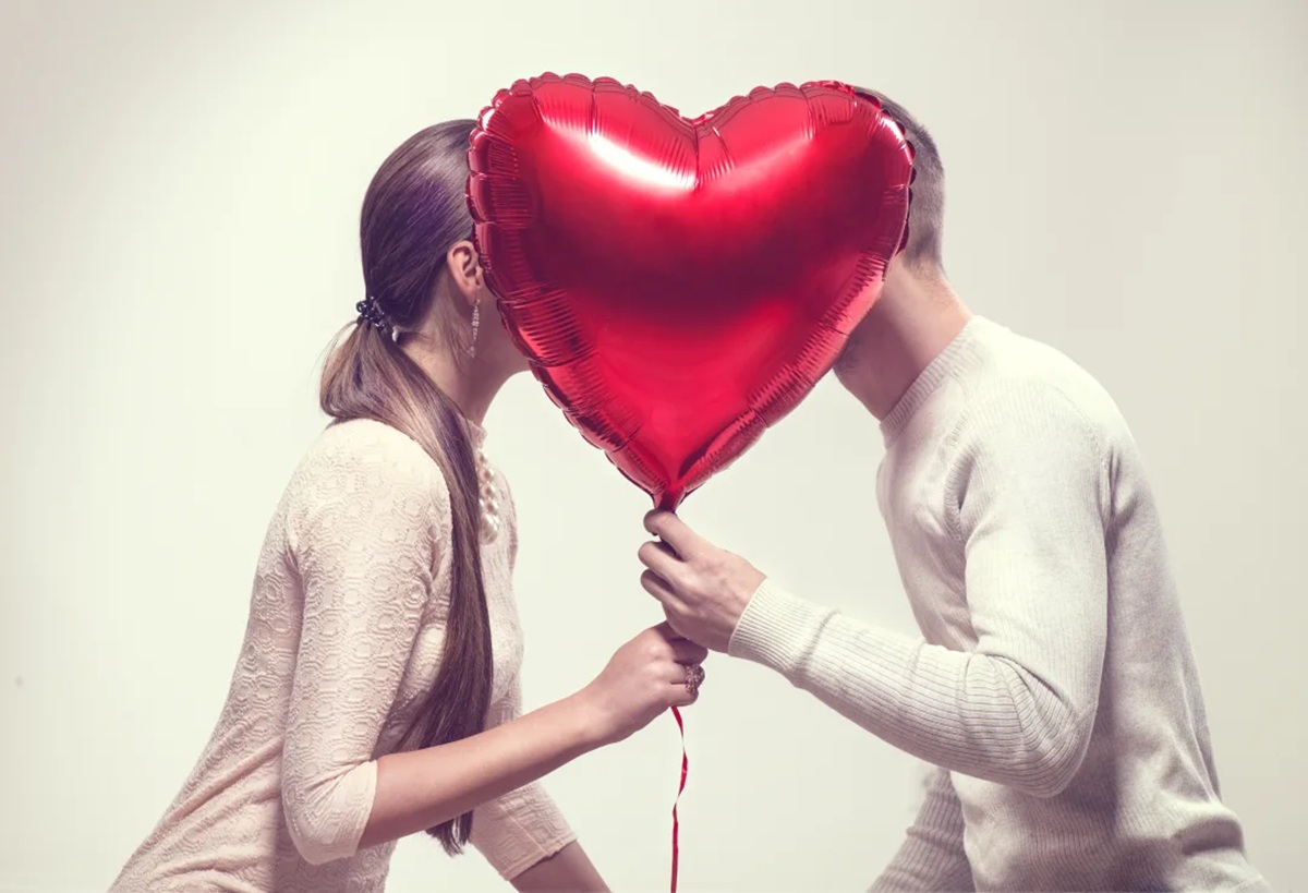 Pareja tapándose la cara con un globo. Día del Infiel