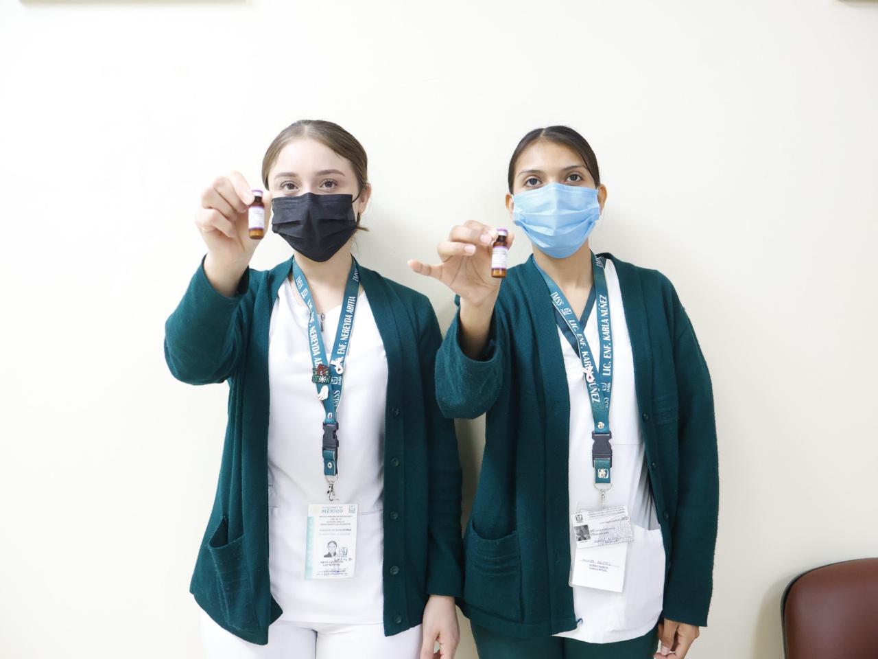 Enfermeras del IMSS mostrando biológico para vacunación