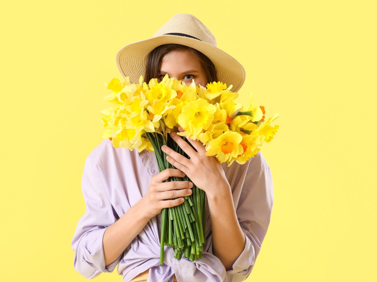 Joven mujer sosteniendo un ramo de flores amarillas