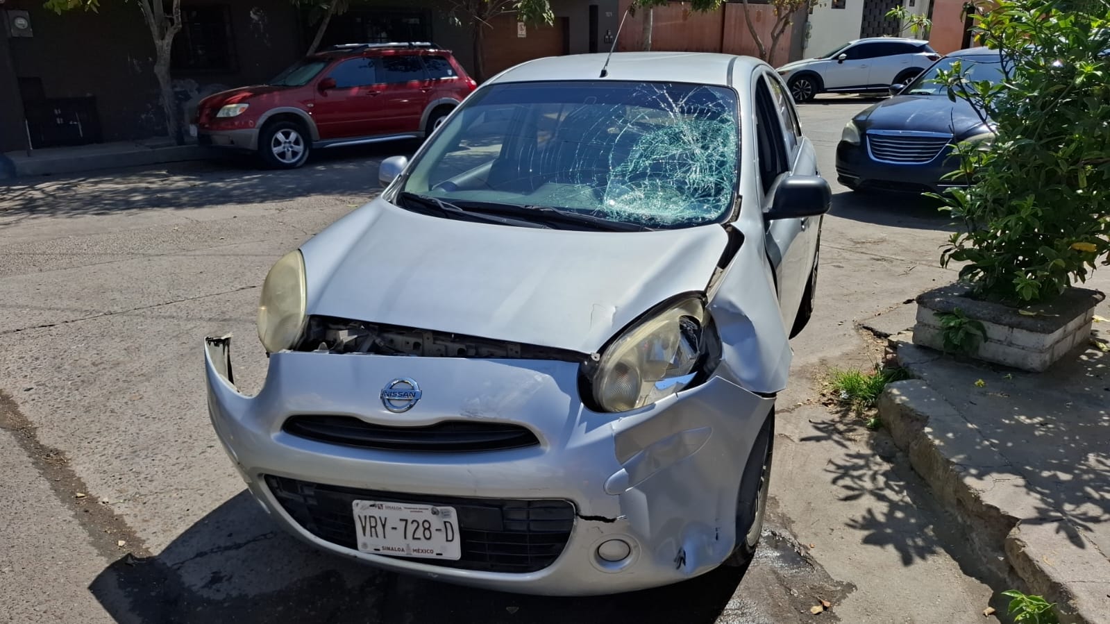 automóvil Nissan March de color gris chocado