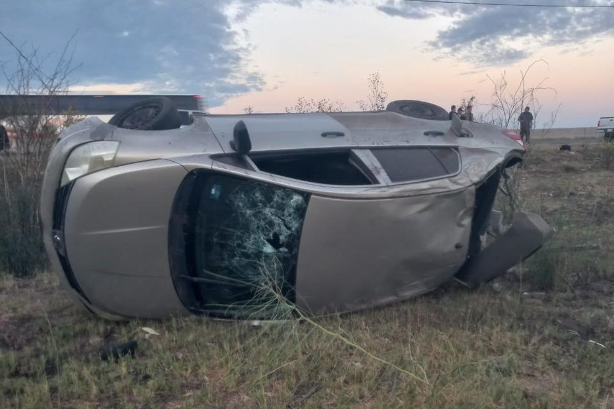Automóvil Nissan Tiida color gris volcado sobre un costado