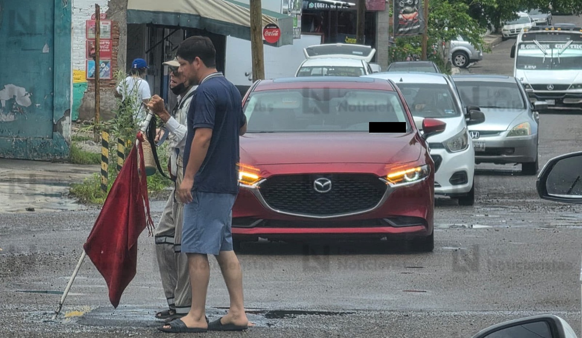 Joven para el tráfico para ayudar a adulto mayor invidente a cruzar vialidad