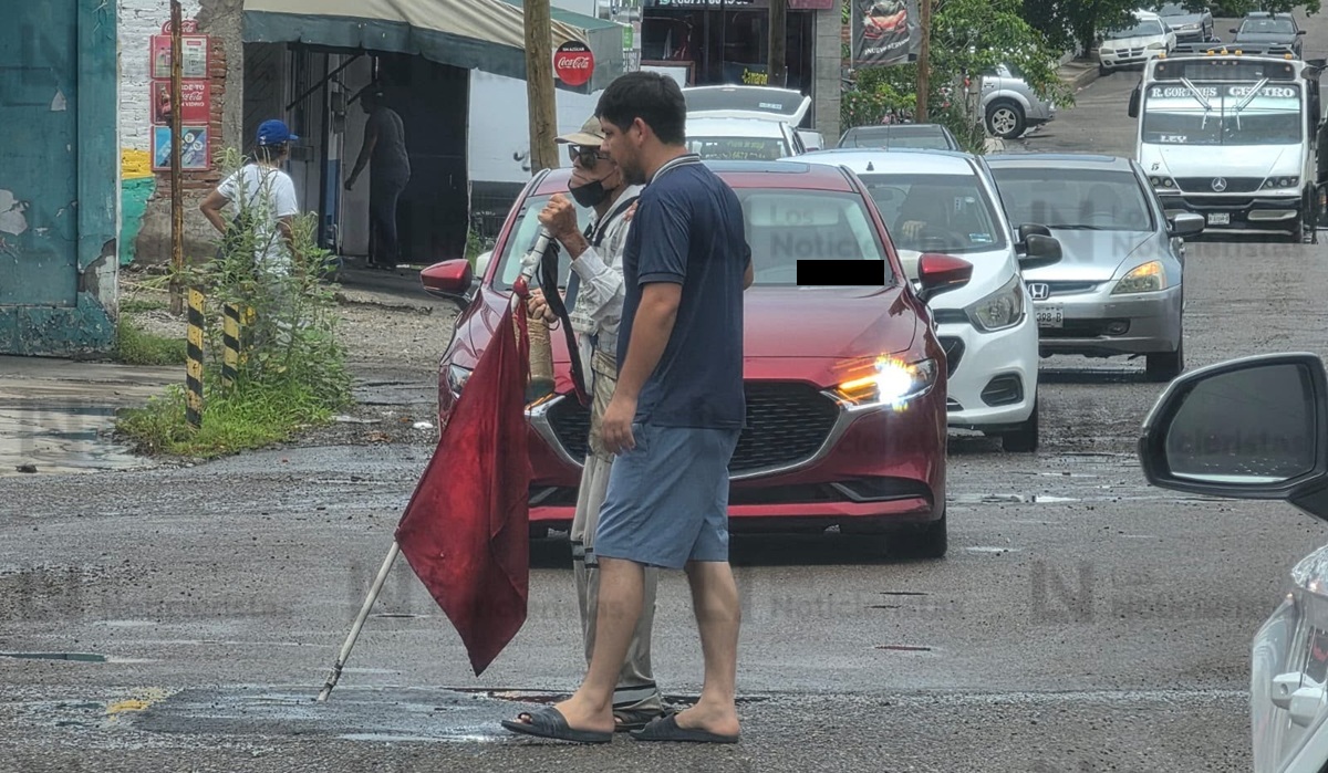 Joven para el tráfico para ayudar a adulto mayor invidente a cruzar vialidad