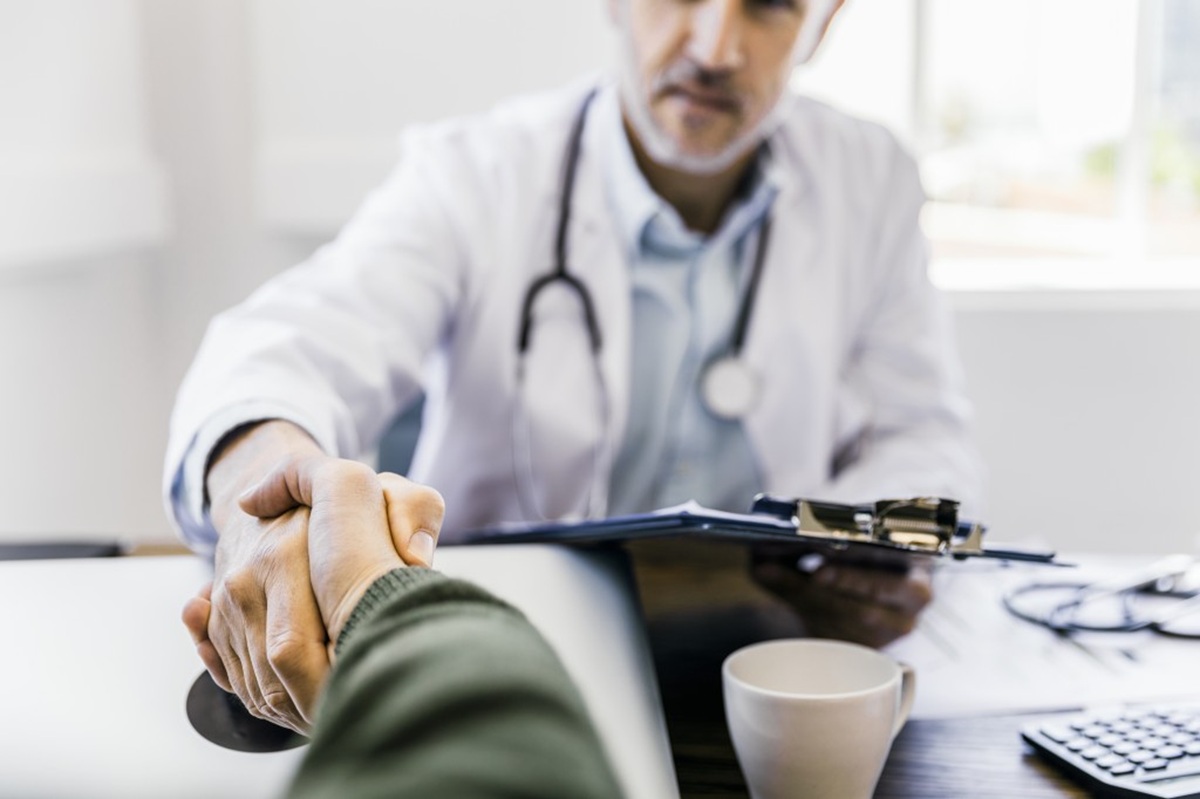 Médico y paciente saludándose en consultorio